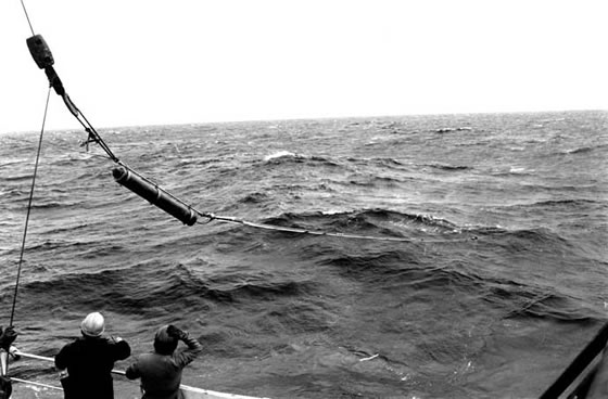 JAn autonomous listening station being deployed from RRS Discovery in the mid 1980's. The ALS consists of a 10m hydrophone unit (furthest from the ship) and recording unit (cylinder above the hydrophone). The ALS was deployed at a depth of approximately 1000m on a mooring.